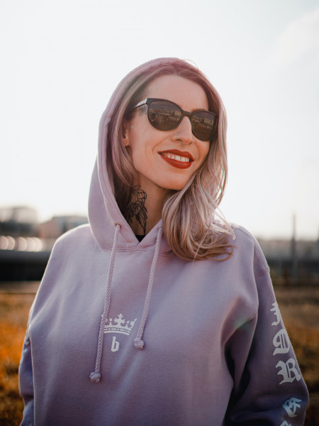 Elodie porte le hoodie 'Basto King' pour hommes et femmes de la marque suisse streetwear bastonnade clothing.